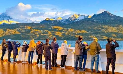 Passengers on deck at the rail of Holland America's Oosterdam in early morning on the 150-mile-long strait known as the Beagle Channel in Chile. Glacier Alley is a shorter section of the channel that showcases 5 tidewater glaciers, named after European countries.